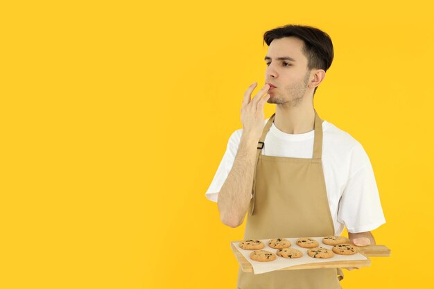 Concept de cuisine jeune homme chef sur fond jaune