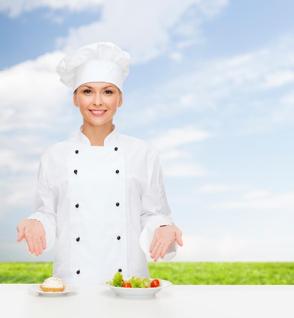 concept de cuisine et de nourriture - chef féminin souriant, cuisinier ou boulanger avec salade et gâteau sur assiettes