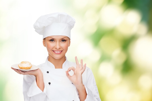 concept de cuisine et de nourriture - chef féminin souriant, cuisinier ou boulanger avec tarte sur assiette et signe ok