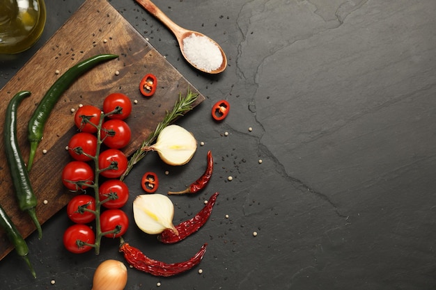 Concept de cuisine Planche à couper en bois et différents produits sur table noire à plat Espace pour le texte