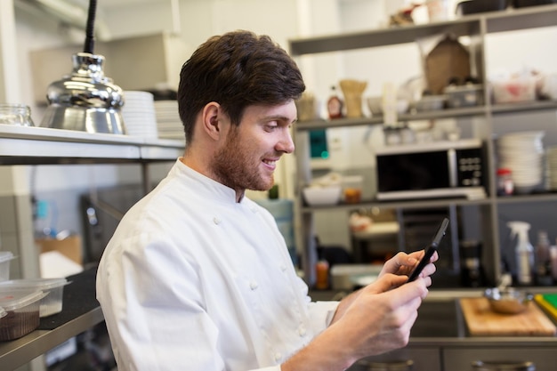 concept de cuisine, de profession et de personnes - cuisinier masculin heureux avec une tablette PC dans la cuisine d'un restaurant