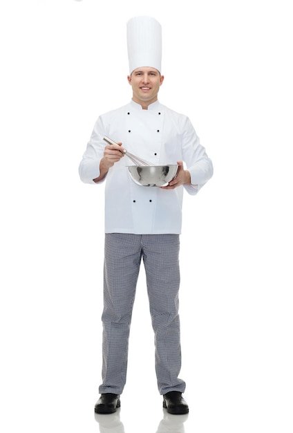 concept de cuisine, de profession et de personnes - heureux chef cuisinier tenant un bol et fouettant quelque chose avec un fouet