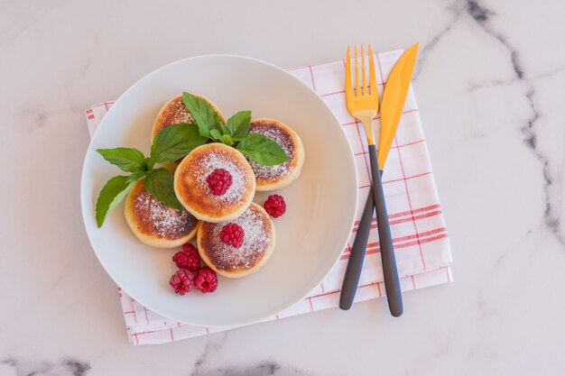 Concept de cuisine russe et ukrainienne. Crêpes Cottage Cheese. Cheesecakes à la framboise et à la menthe sur une assiette