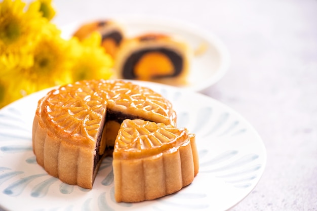 Concept de cuisine traditionnelle du festival de la mi-automne - Beau gâteau de lune coupé sur une plaque à motif bleu sur fond blanc avec fleur, gros plan, espace pour copie