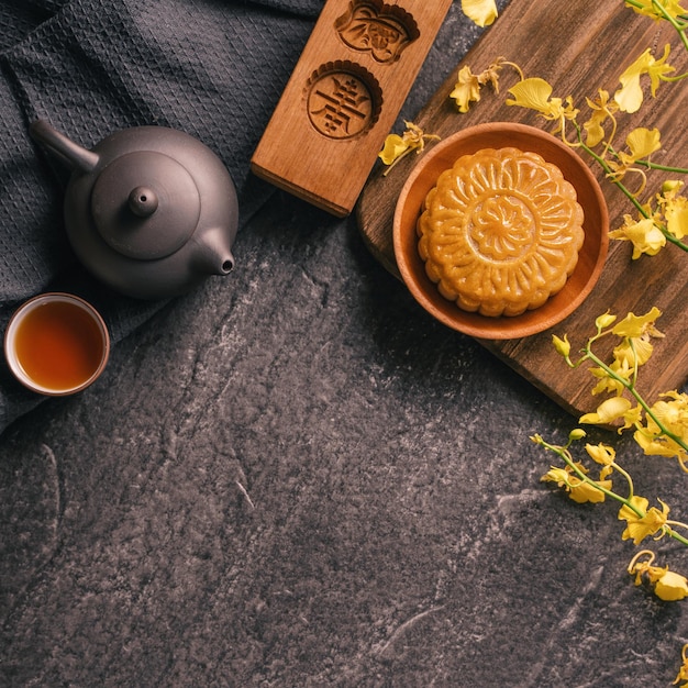 Concept de cuisine traditionnelle du Festival de la mi-automne Beau gâteau de lune sur une table en ardoise noire avec moule à pâtisserie thé fleur vue de dessus espace de copie plat