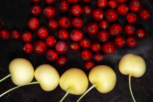 Concept de cuisine végétarienne Groseilles rouges juteuses sucrées et cerises jaunes sur fond sombre Vue d'en haut