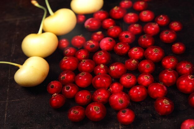 Concept de cuisine végétarienne Groseilles rouges juteuses sucrées et cerises jaunes sur fond sombre Vue d'en haut