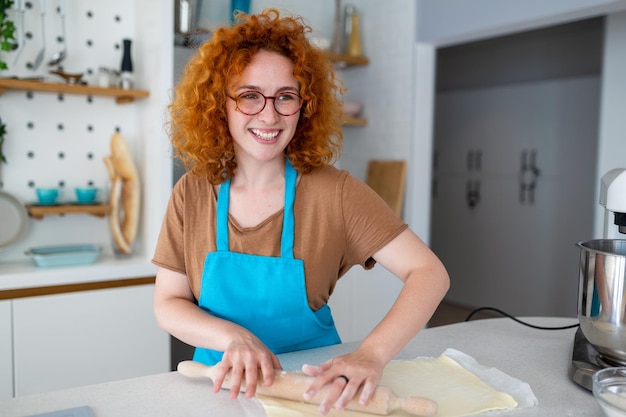 Concept de cuisson Portrait d'une femme joyeuse pétrir la pâte dans l'intérieur de la cuisine