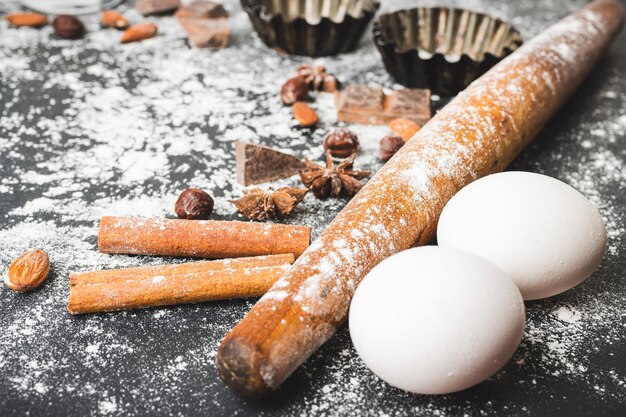 Concept de cuisson rouleau à pâtisserie oeufs sous forme de cupcake et ingrédients alimentaires sur fond sombre préparer pour la cuisson