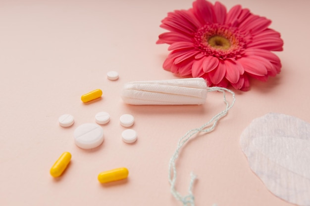 Concept de cycle menstruel féminin Pilules de serviettes hygiéniques et tampon isolés sur fond rose gros plan