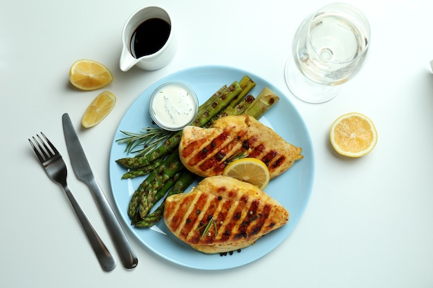 Concept de délicieux déjeuner avec poulet grillé et asperges sur fond blanc