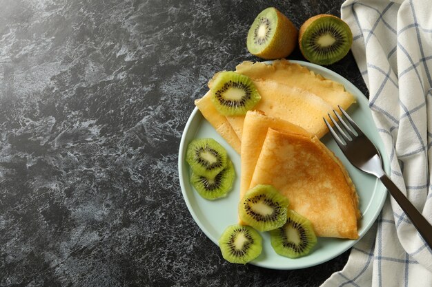 Concept de délicieux petit-déjeuner avec des crêpes au kiwi sur fond noir fumé