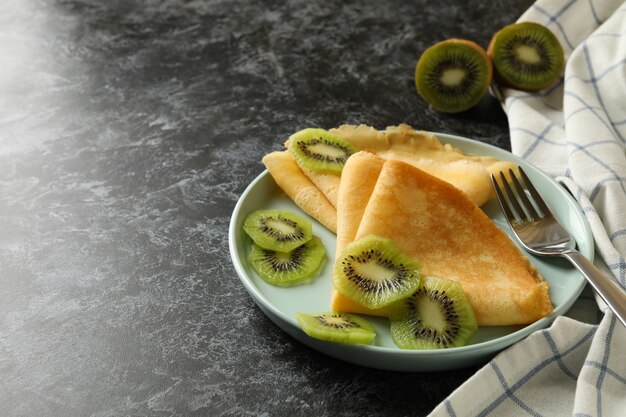 Concept de délicieux petit-déjeuner avec des crêpes au kiwi sur une surface fumée noire