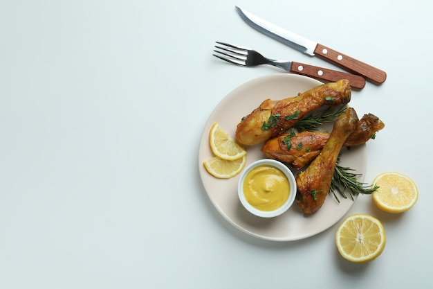 Concept de délicieux repas avec assiette de pilons de poulet rôti sur fond blanc