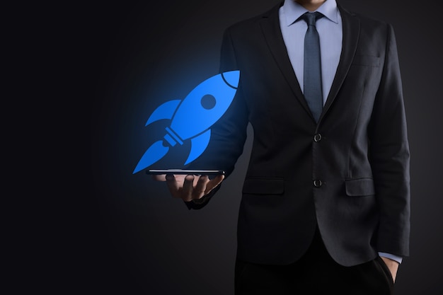 Concept de démarrage avec un homme d'affaires tenant une icône de fusée numérique abstraite, la fusée lance et monte en flèche