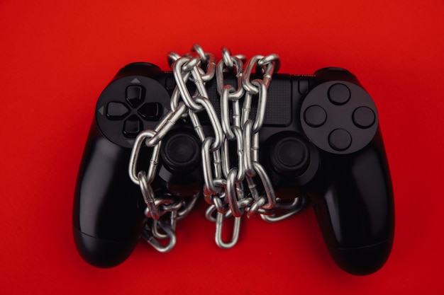 Concept de dépendance au jeu. La manette de jeu est attachée par une chaîne.