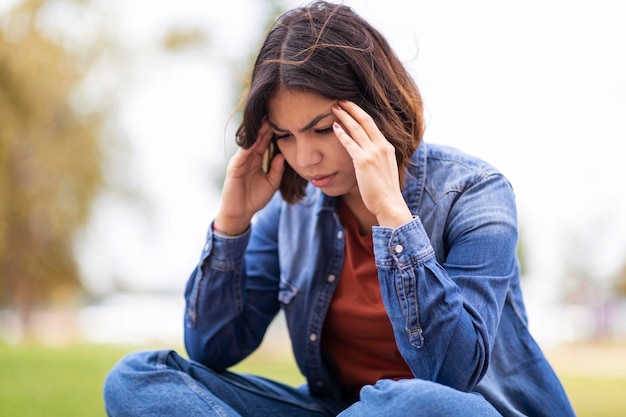 Concept de dépression Femme arabe bouleversée assise à l'extérieur et touchant la tête dans le désespoir