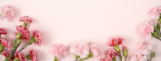 Concept de design de conception de voeux de vacances de fête des mères avec bouquet d'oeillets sur fond de table rose pastel