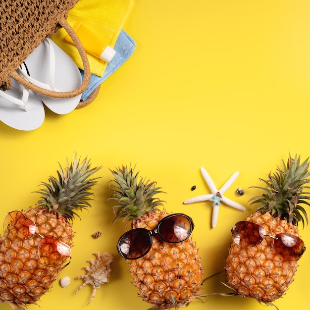 Concept de design de fond de fruits d'été. Vue de dessus de la plage de vacances avec coquillages, ananas et feuilles de palmier sur fond jaune.