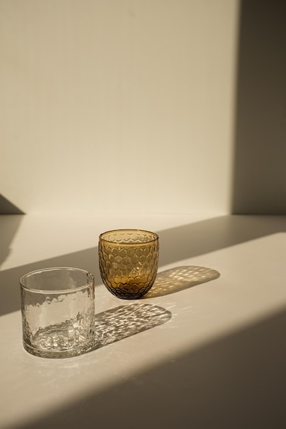 Concept de design d'intérieur moderne esthétique de luxe minimal Verre de cristal de Bohême avec ombre scintillante de la lumière du soleil sur fond beige neutre