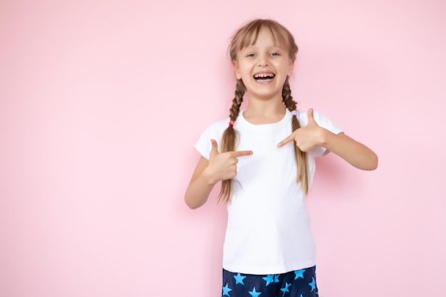 concept de design de t-shirt - petite fille souriante en t-shirt blanc vierge pointant sur elle-même