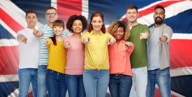concept de diversité, de choix, d'ethnicité et de personnes - groupe international d'hommes et de femmes souriants et heureux pointant le doigt sur vous sur fond de drapeau anglais