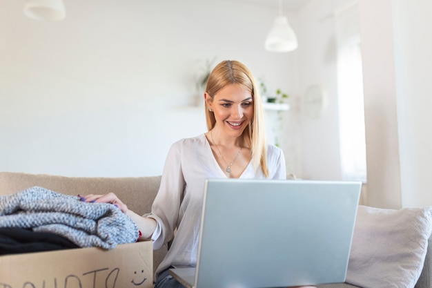 Concept de don. Femme tenant une boîte de don avec plein de vêtements. Une femme tenant un livre et des vêtements donne une boîte. Vêtements dans une boîte pour le don de concept et le recyclage de la réutilisation