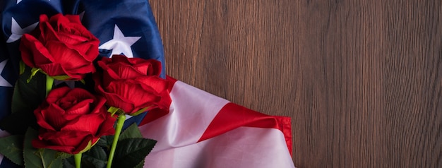 Concept du jour de l'indépendance des États-Unis ou du jour du souvenir. Drapeau national et rose rouge sur fond de table en bois foncé.