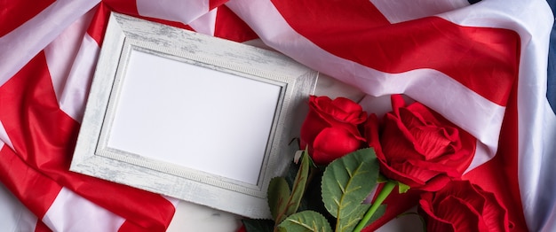 Concept du jour de l'indépendance des États-Unis ou du jour du souvenir. Drapeau national et rose rouge sur fond de table en marbre clair avec cadre photo.