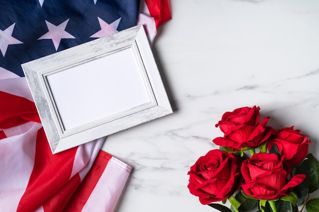 Concept du jour de l'indépendance des États-Unis ou du jour du souvenir. Drapeau national et rose rouge sur fond de table en marbre clair avec cadre photo.