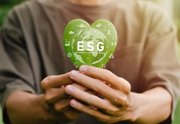 Le concept du jour de la Terre Green Energy ESG est dans la paume de votre main avec une feuille en forme de coeur pour l'environnement