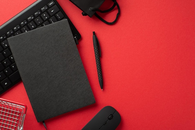 Photo concept du vendredi noir photo vue de dessus d'un stylo planificateur noir, d'un clavier de souris d'ordinateur, d'un sac en papier et d'un panier d'achat sur fond rouge isolé avec espace de copie