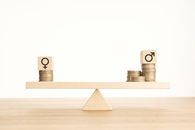 Photo concept d'écart salarial entre hommes et femmes bloc de bois avec symbole de genre sur des pièces empilées sur une balançoire