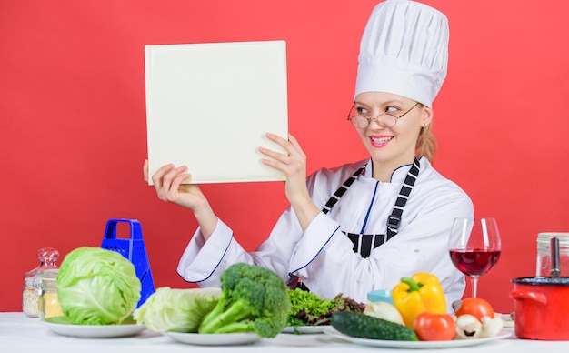 Concept d'école culinaire Femme en chapeau et tablier sait tout sur les arts culinaires Cuisine traditionnelle Expert culinaire Femme chef cuisiner des aliments sains Fille lire livre top meilleures recettes culinaires