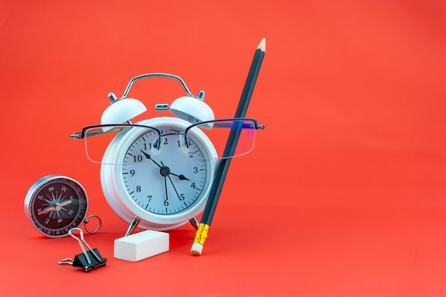 Concept Education ou affaires Réveil et lunettes de professeur Objets commerciaux isolés sur fond coloré Concept de retour à l'école