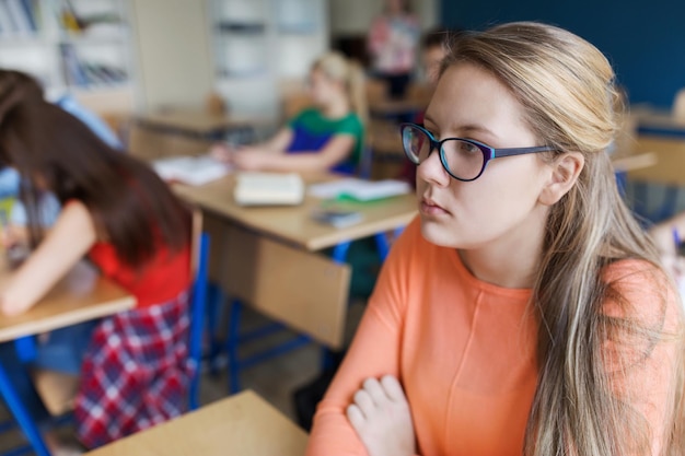 concept d'éducation, d'apprentissage et de personnes - étudiante en lunettes à la leçon d'école