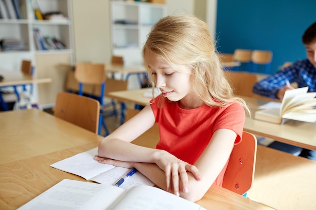 concept d'éducation, d'apprentissage et de personnes - fille étudiante avec livre et cahier à la leçon d'école