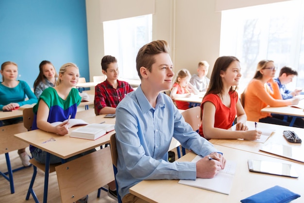 concept d'éducation, d'apprentissage et de personnes - groupe d'étudiants avec des cahiers à la leçon d'école