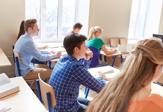 concept d'éducation, d'apprentissage et de personnes - groupe d'étudiants avec des cahiers à la leçon d'école