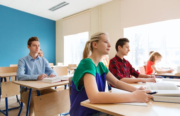 concept d'éducation, d'apprentissage et de personnes - groupe d'étudiants avec des livres à l'école