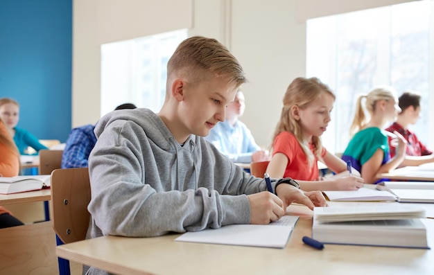 concept d'éducation, d'apprentissage et de personnes - groupe d'étudiants avec des livres écrivant un test scolaire