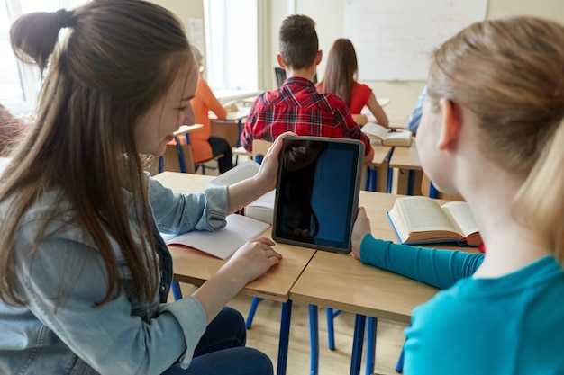 concept d'éducation, d'apprentissage, de technologie, d'amitié et de personnes - étudiantes heureuses avec tablette pc au lycée