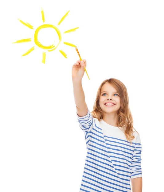 concept d'éducation, d'école et d'écran imaginaire - jolie petite fille dessinant le soleil avec une brosse