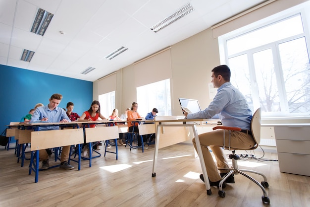 concept d'éducation, d'école, d'enseignement, de technologie et de personnes - groupe d'étudiants et d'enseignants heureux avec un ordinateur tablette