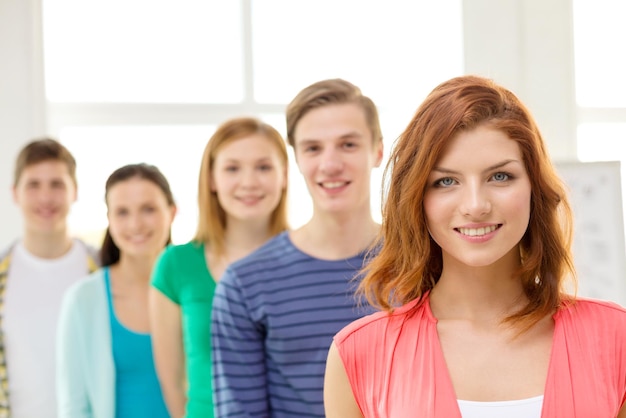 concept d'éducation et d'école - groupe d'étudiants souriants avec une adolescente devant
