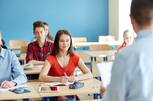 concept d'éducation, d'école et de personnes - groupe d'étudiants et d'enseignants heureux avec des papiers ou des tests