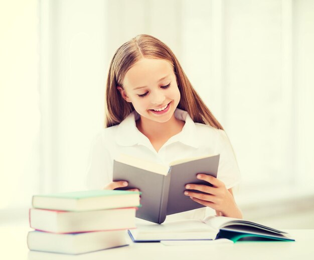 concept d'éducation et d'école - petite étudiante étudiant et lisant des livres à l'école