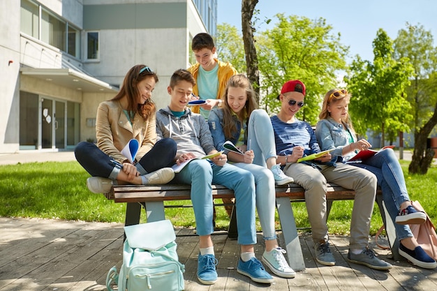 concept d'éducation, d'école secondaire et de personnes - un groupe d'étudiants adolescents heureux avec des cahiers d'apprentissage dans la cour du campus