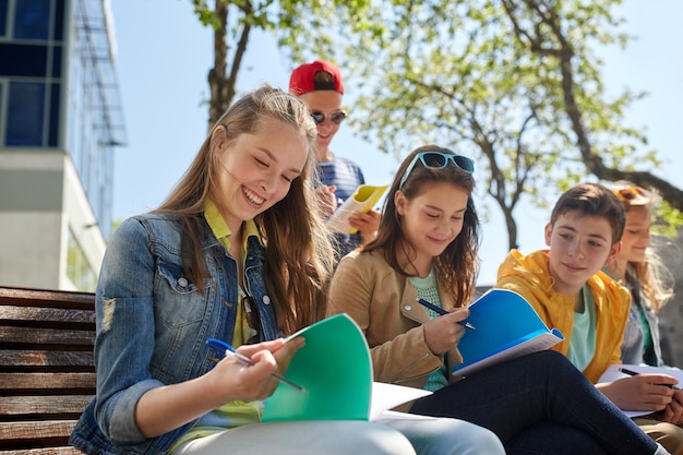 concept d'éducation, d'école secondaire et de personnes - un groupe d'étudiants adolescents heureux avec des cahiers d'apprentissage dans la cour du campus