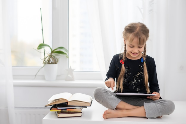 concept d'éducation, d'école, de technologie et d'internet - petite étudiante avec tablette à la maison